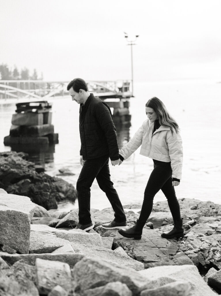 engagement session coastal rocky beach maine couple walking holding hands
