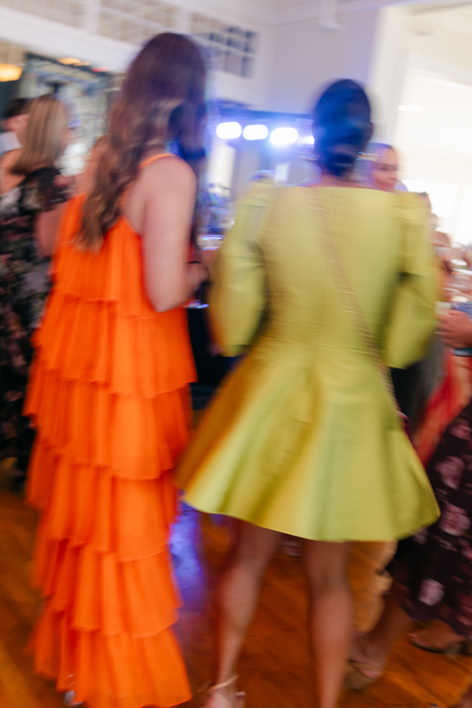 Colorful guest dress code ideas featuring vibrant orange and red attire that complement citrus florals at a joyful Maine wedding.