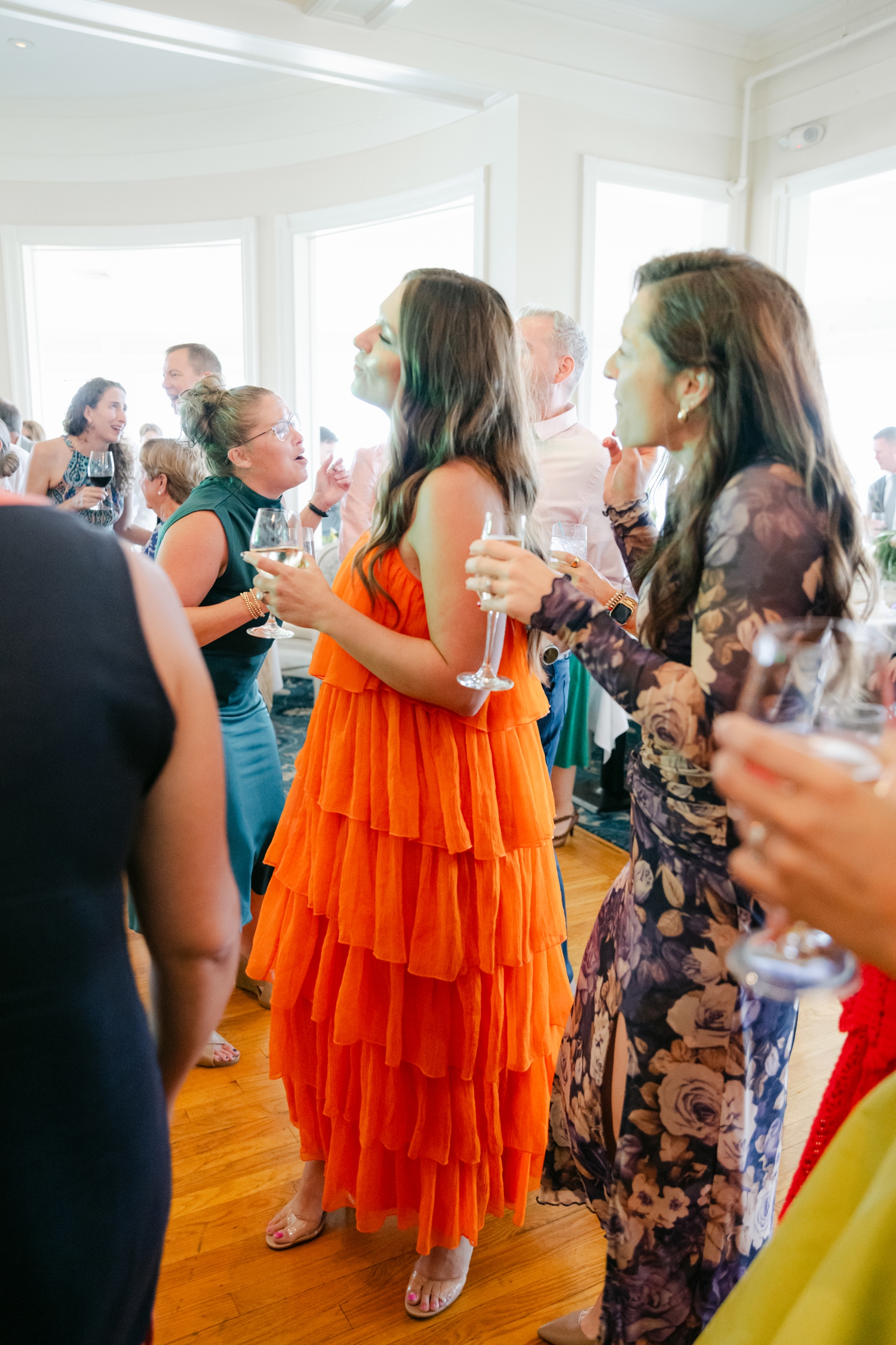Colorful guest attire with vibrant citrus tones of orange, pink, and chartreuse illuminating the Maine coastline.