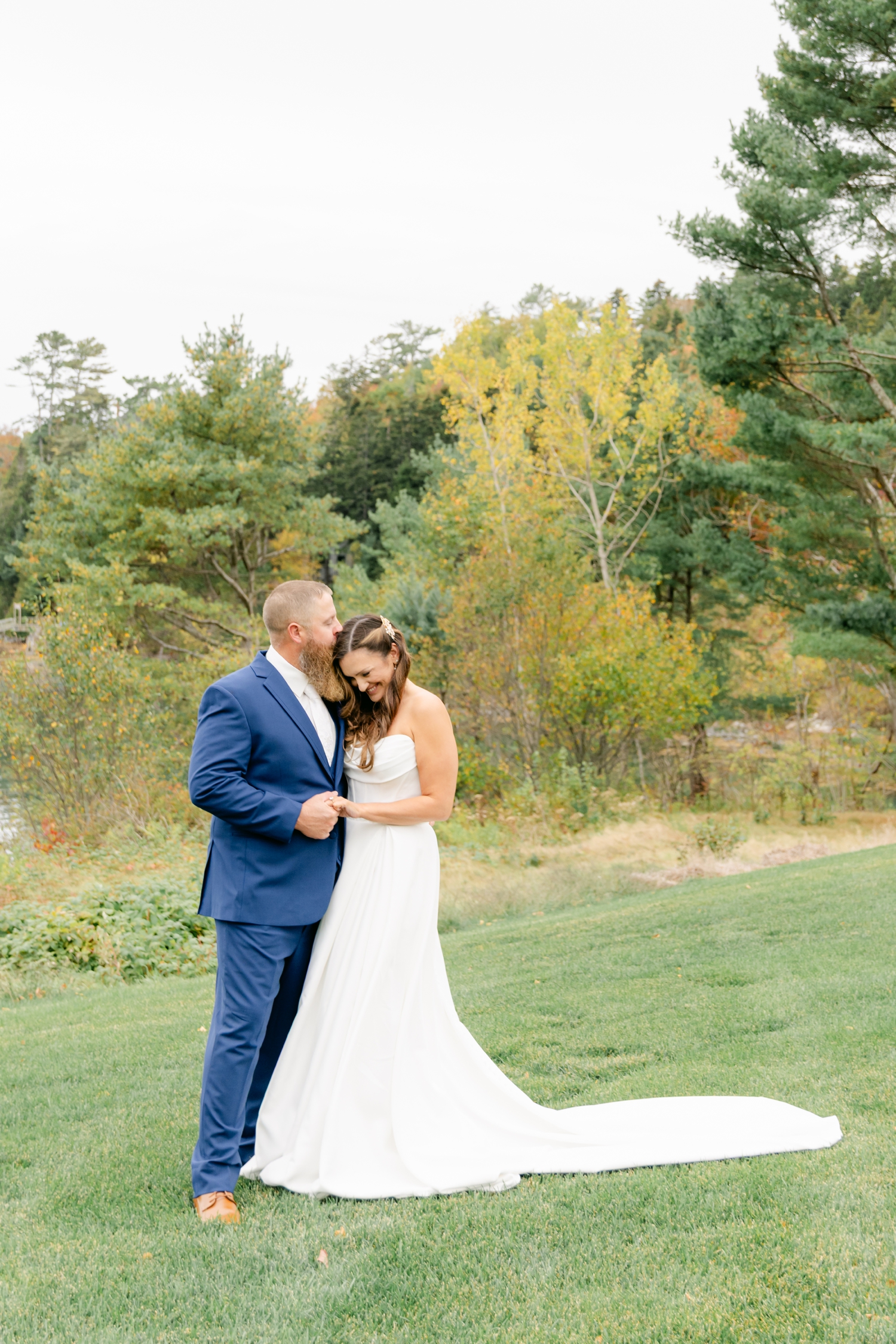 Bride and Groom standing outside the Asticou Inn during their autumn micro-wedding with soft foliage behind them.