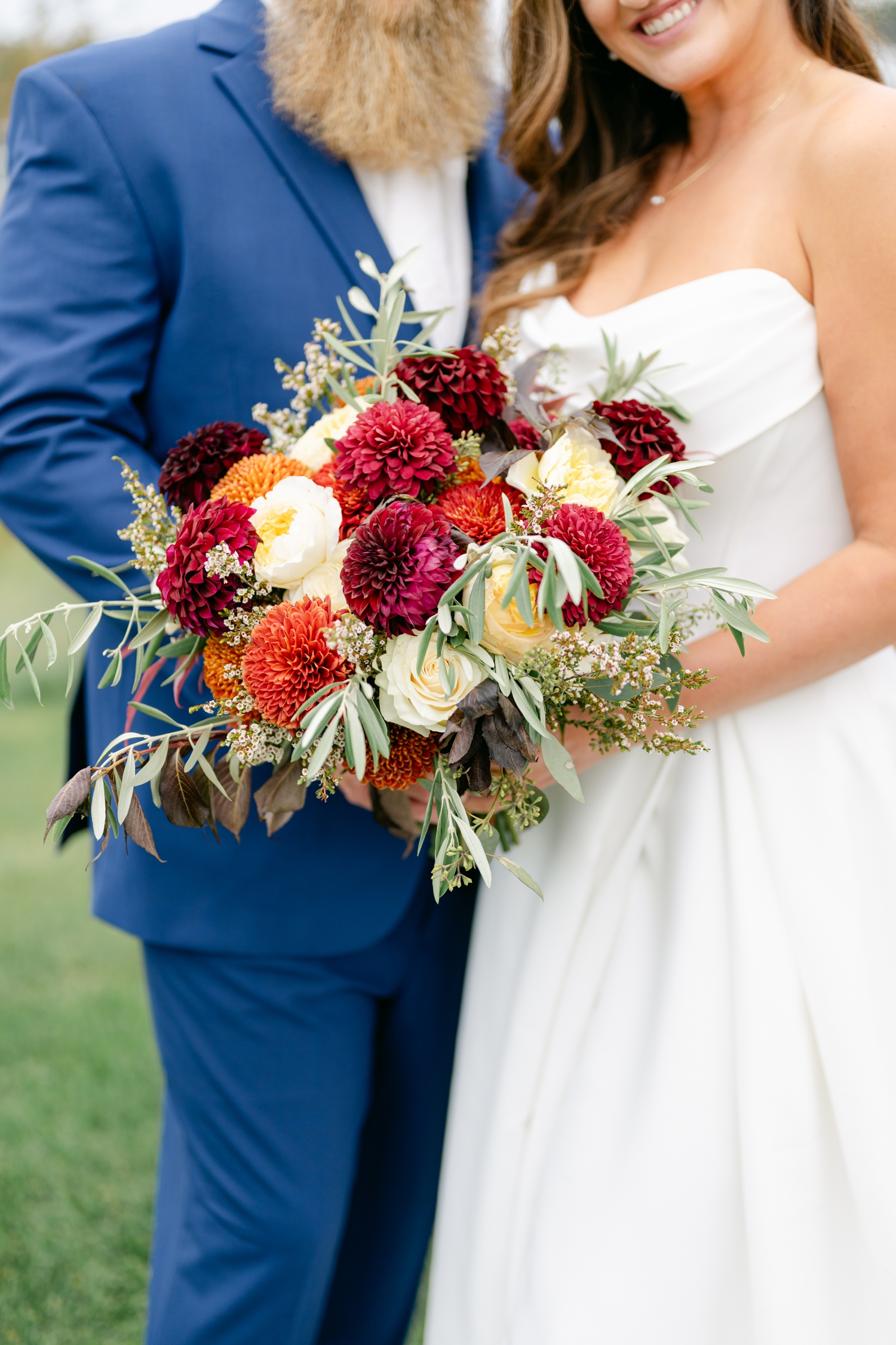 Bride and Groom standing outside the Asticou Inn during their autumn micro-wedding with soft foliage behind them.
