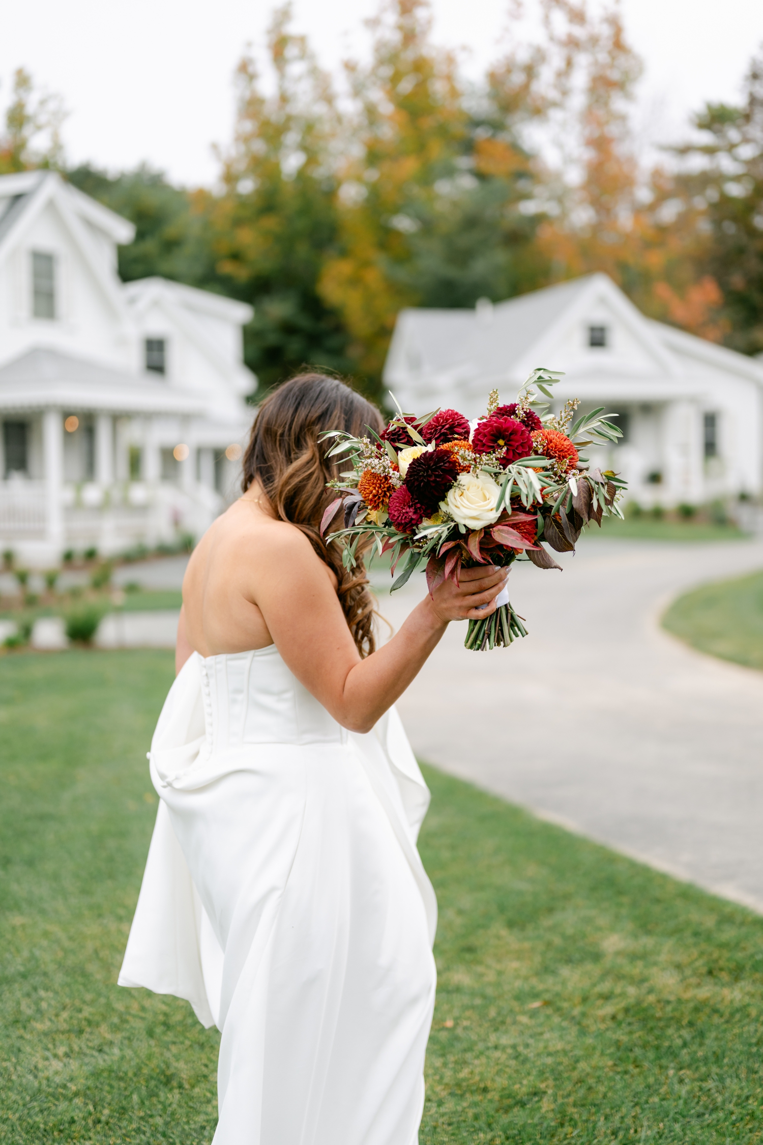 Bride and Groom standing outside the Asticou Inn during their autumn micro-wedding with soft foliage behind them.