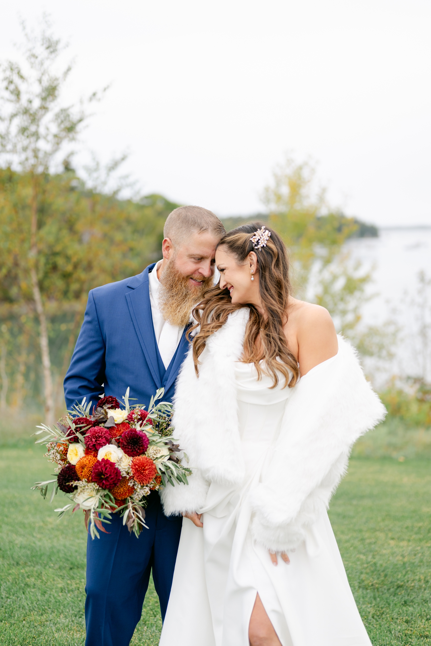 Bride and Groom standing outside the Asticou Hotel during their autumn micro-wedding with soft foliage behind them.