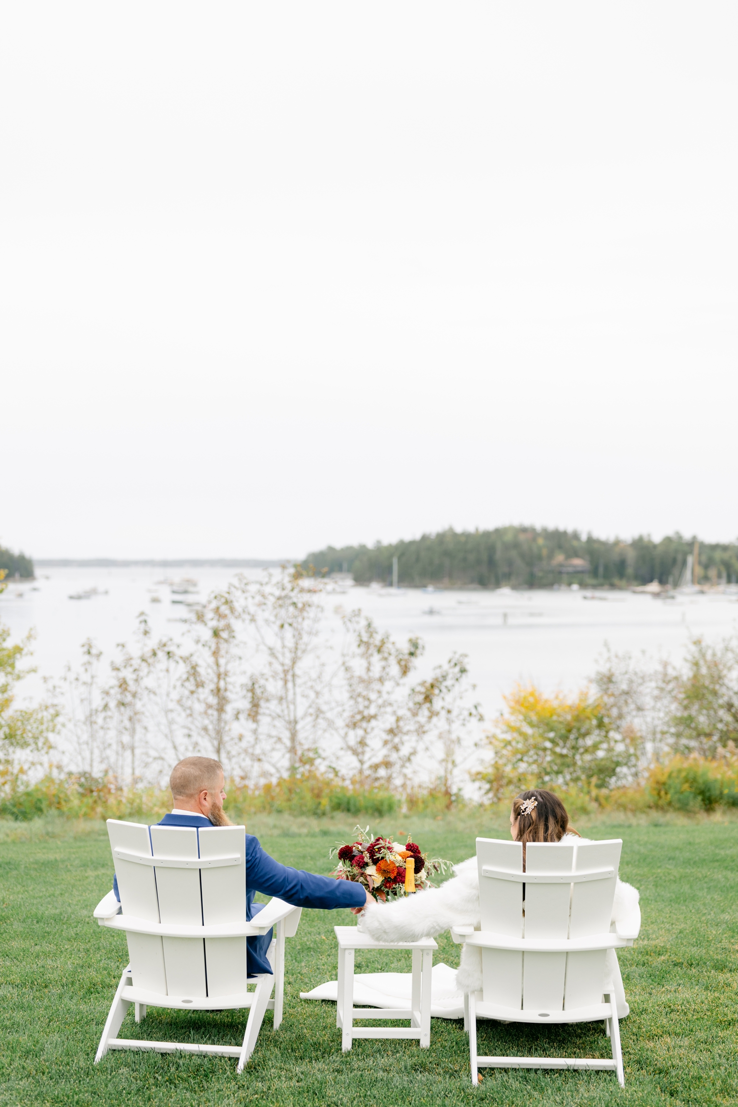 Bride and Groom standing outside the Asticou Hotel during their autumn micro-wedding with soft foliage behind them.