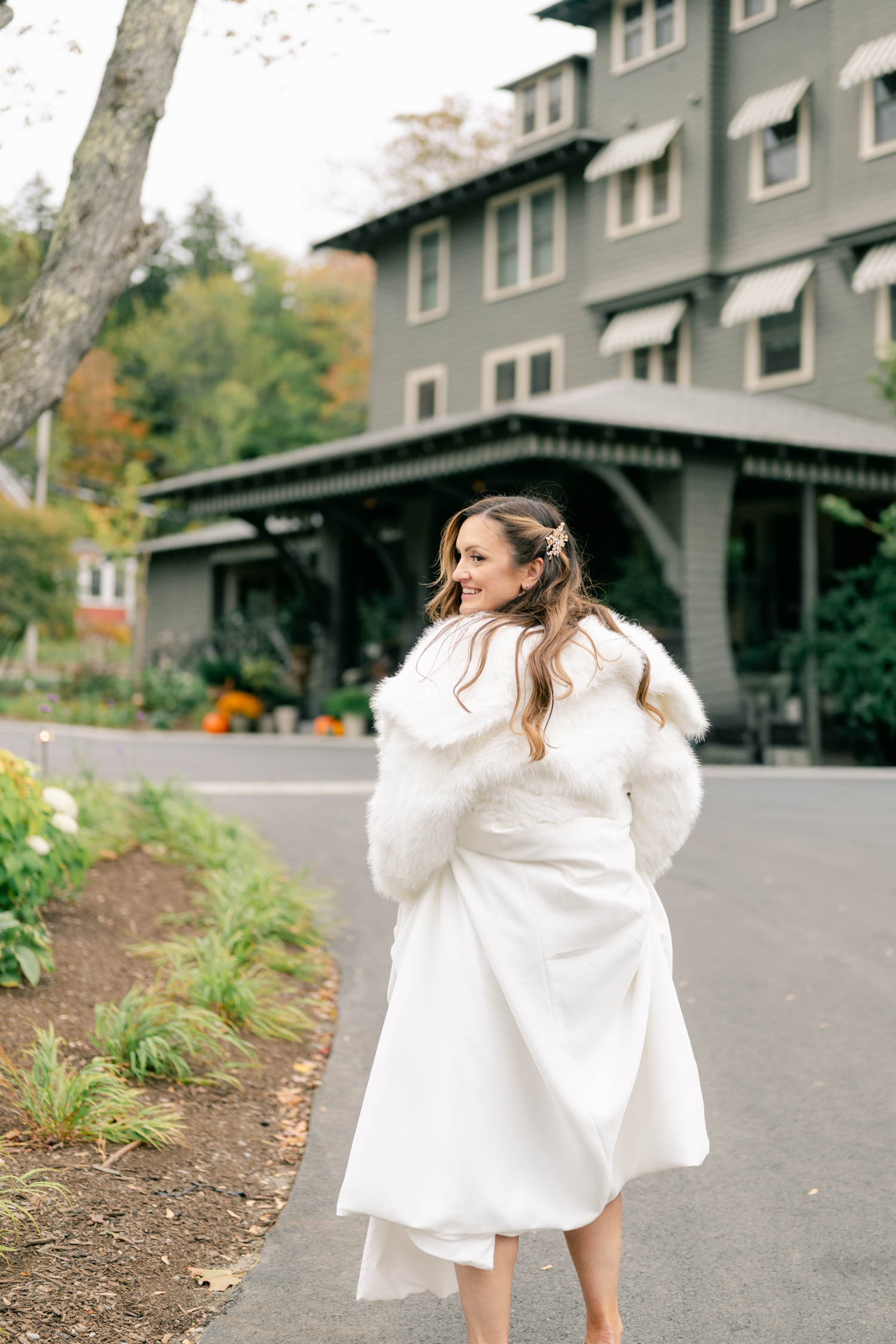 Bride and Groom standing outside the Asticou Hotel during their autumn micro-wedding with soft foliage behind them.