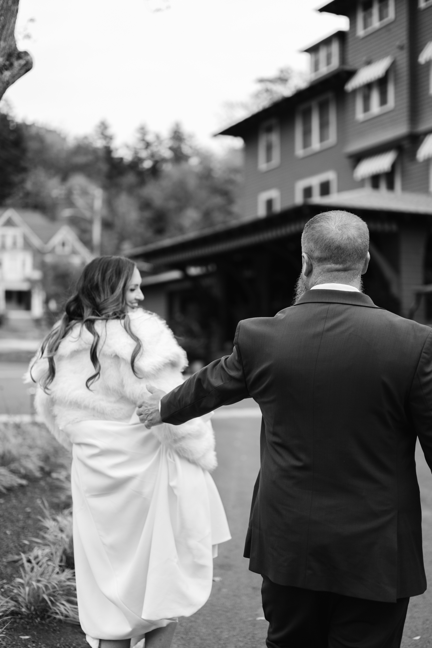 Bride and Groom standing outside the Asticou Hotel during their autumn micro-wedding with soft foliage behind them.