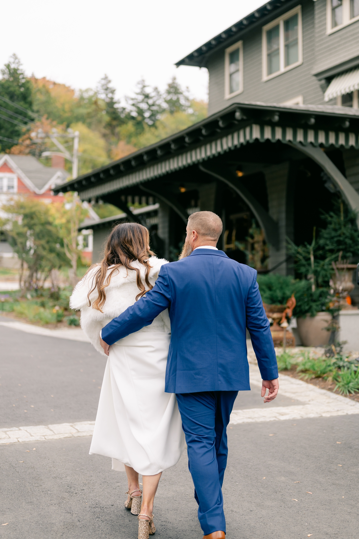Bride and Groom standing outside the Asticou Inn during their autumn micro-wedding with soft foliage behind them.