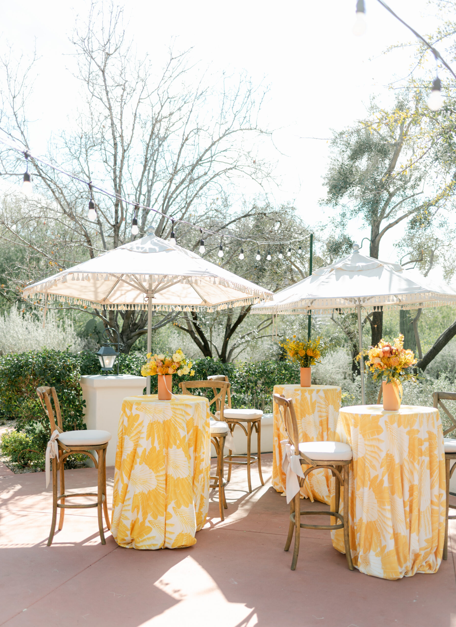 Outdoor wedding cocktail hour ideas with patterned linens, umbrellas, and seated guest tables