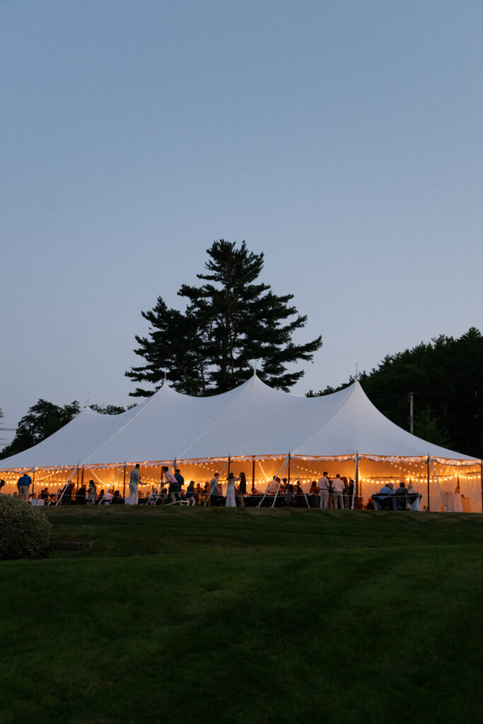 sailcloth tent glowing at dusk at a Maine wedding welcome party