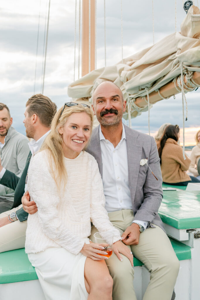 couple smiling together on a sailboat at their Bar Harbor Maine wedding welcome party
